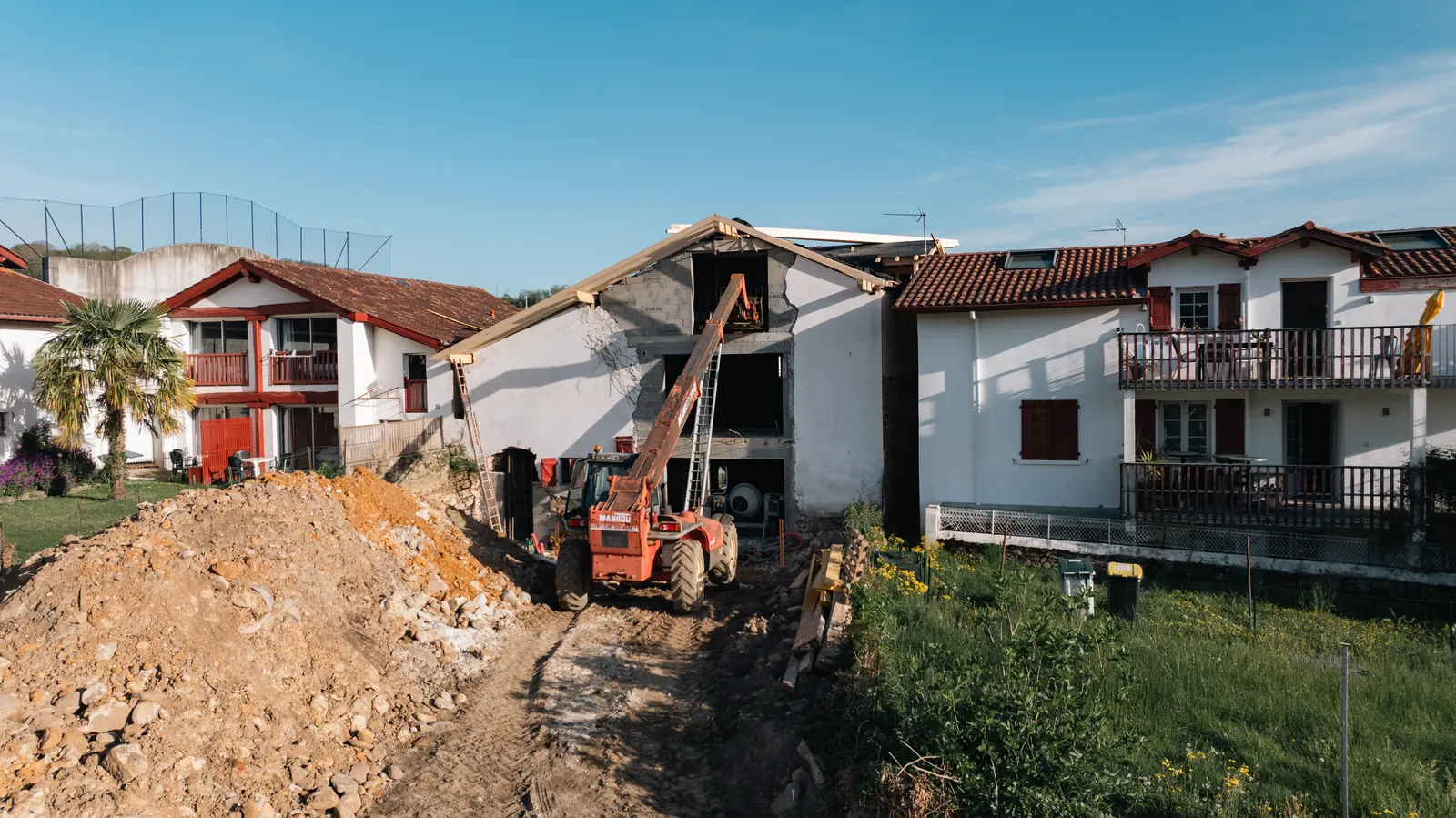 Chariot télescopique levant les bois de charpente d'une maison en travaux au Pays Basque