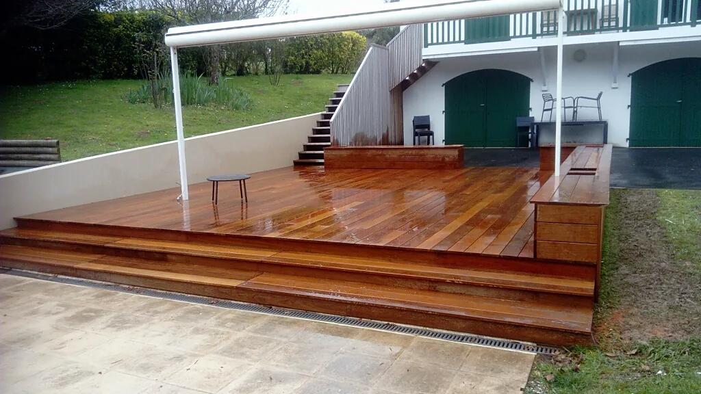Terrasse en lames de bois exotique avec emmarchement et banc intégré devant une maison basque